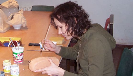 Moteris dekoruoja keramikos dirbinį studijoje